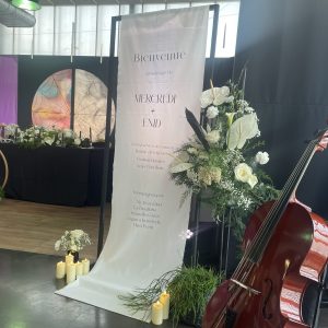 Arche noire de signalétique pour panneau de bienvenue mariage avec tissu suspendu et décoration florale